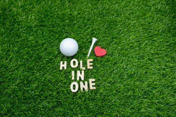 Golf hole in one with golf ball and tee on green grass.