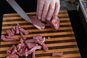 Organic produce sold at farmer's market. A close-up view on the hands of a chef slicing foie gras,...