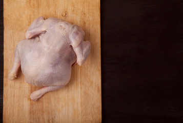 Raw chicken on a wooden board on a black background. Copy spaes.