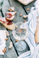 Bruschettes and a picnic with prosciutto. White wine with a glass in nature in Italy.