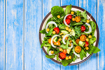 Greek salad with chickpea on wooden background