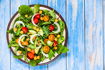 Greek salad with chickpea on wooden background