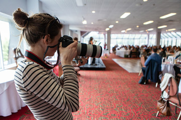 Atmosphere during corporate conference. A side profile view of a professional female photographer...