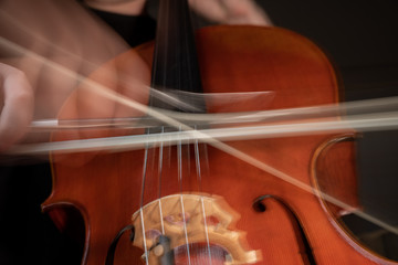 A young cellist practices intensely in this close up high resolution photo of strings, cello, and bow