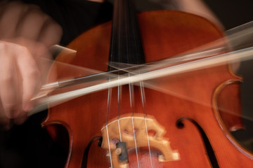 A young cellist practices intensely in this close up high resolution photo of strings, cello, and bow