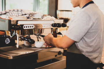 Male barista preparing coffee for the client.