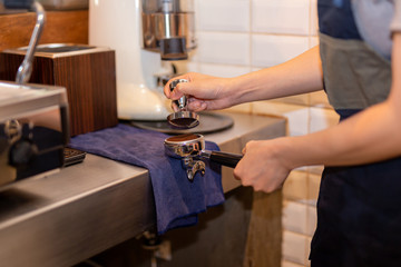 Barista with tamper and piston, portafilter making fresh coffee.