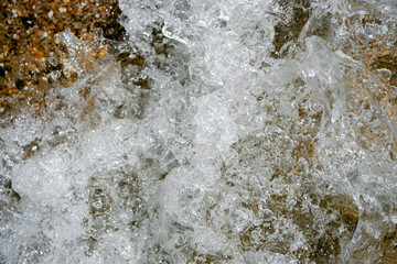 Splashing waves on the seashore close-up. White foam waves on a sunny day. View from above
