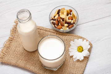 Fototapeta na wymiar Bottle and glass of milk, bowl with muesli and daisy flower on gray background