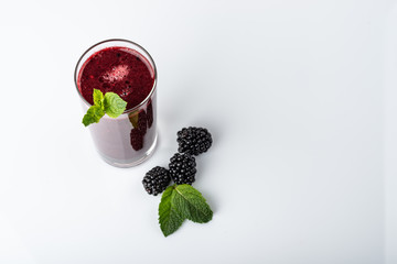 Glass of blackberry smoothie on white background. Top view.
