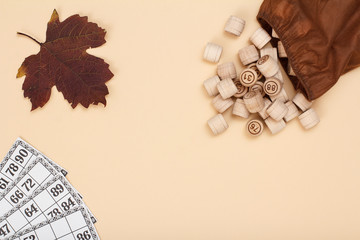 Wooden lotto barrels with brown bag and game cards on beige background.