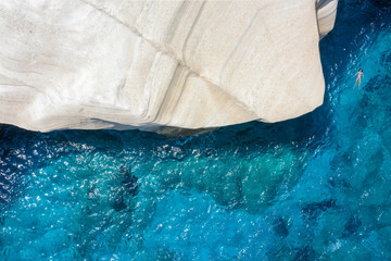 Frau im Bikini treibt neben den markanten Felsen im türkisem Meer von Sarakiniko auf Milos,...
