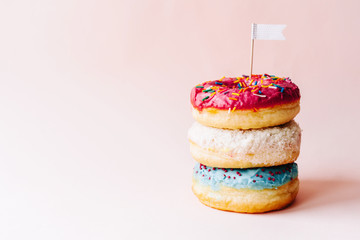 Three multi-colored glazed cream donuts stacked on each other