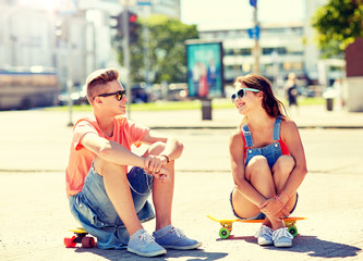 summer holidays, extreme sport and people concept - happy teenage couple with short modern cruiser...