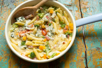 Pasta with vegetables and cheese sauce. Pasta with bacon, yellow peppers, broccoli, tomatoes and blue cheese 