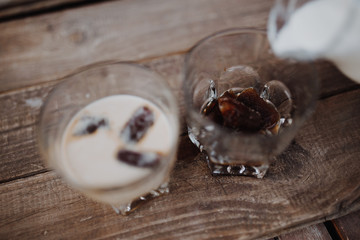 Pour milk in delicious coffee ice cubes on wood table