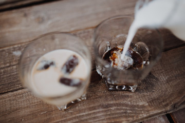 Pour milk in delicious coffee ice cubes on wood table