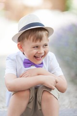 A little boy of 5 years old walks in a flowered park. Lavender. Spring. Portrait of a boy in a hat with a bow tie.