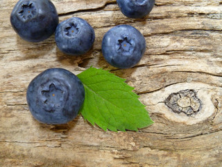 Bowl of fresh blueberries on rustic wooden old table. Freshly picked blueberries in bowl. Healthy organic fruit background. Organic food raw blueberries and mint leaf for healthy lifestyle.