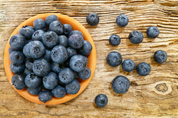 Bowl of fresh blueberries on rustic wooden old table. Freshly picked blueberries in bowl. Healthy organic fruit background. Organic food raw blueberries and mint leaf for healthy lifestyle.