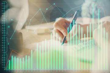 Financial forex graph displayed on hands taking notes background. Concept of research. Multi exposure