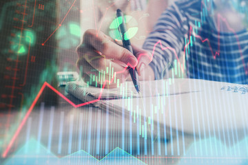 Financial forex graph drawn over hands taking notes background. Concept of research. Double exposure
