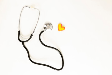 Heart health and prevention concept. Stethoscope and red heart of crochet on white isolated background with space for text.