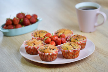Tasty summer dessert: chocolate chip and fresh strawberry muffins on a pink plate decorated by fresh strawberries