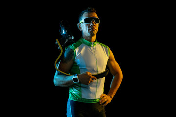 Athlete with disabilities or amputee on black background in neon light. Professional male runner with leg prosthesis training and practicing in studio. Disabled sport and healthy lifestyle concept.