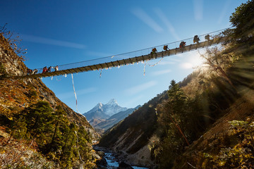 Trekkers on rope hanging suspension bridge on the way to Mount Everest base camp near Namche Bazar - Nepal - obrazy, fototapety, plakaty