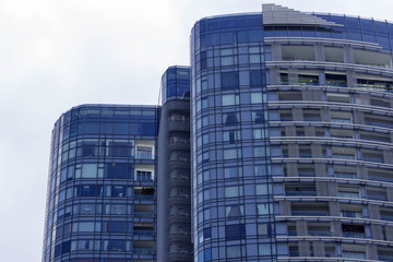 Fototapeta premium Tall building facade windows front view. Green windows facade of a tall building