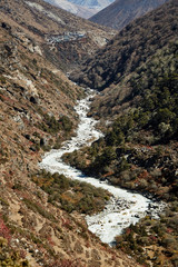 Harsh mountain landscape with a rocky bottom of the valley and a glacial river.
