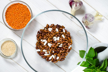 The bean diet. Beans, lentils, sesame garlic and basil in glass plates stand on a wooden table