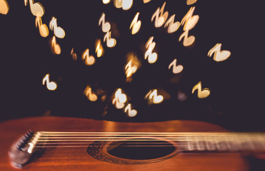 Acoustic guitar with musical note bokeh in background