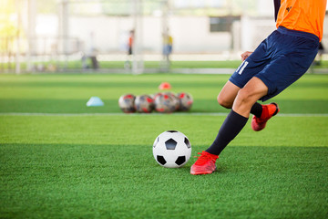Soccer player speed run to shoot ball to goal on artificial turf. Soccer player training or football match.