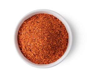 Crushed red chili pepper in white bowl on white background. top view