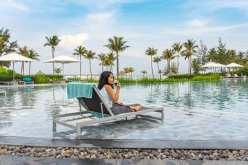 Young Asian woman enjoy red wine at beautiful swimming pool