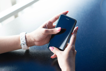 Well-groomed hands of the girl with pink manicure hold the smartphone. A girl using a smartphone