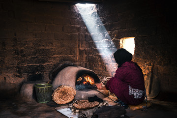Berber woman making the bread in a mud house, old moroccan traditions