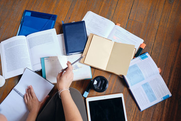 Close up photo of girl holding pencil in hand studying with tablet,books and cup of coffee to go on floor at cozy home