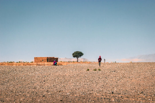 A women, tree and mud house in the Sahara desert. Reportage in Africa