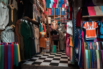 Fototapeta na wymiar Men discussing in a shop for clothes and fabrics in the center of Marrakech, Morocco