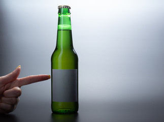 Green glass beer bottle and female hand pointing a bottle