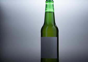 Green glass beer bottle on gray background