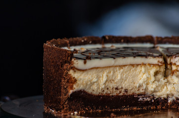 close-up of delicious cheesecake with chocolate bottom on blurred background in low key