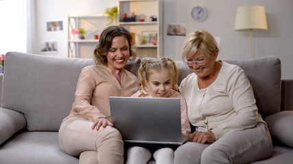 Grandmother and daughter teaching child use laptop application, playing game