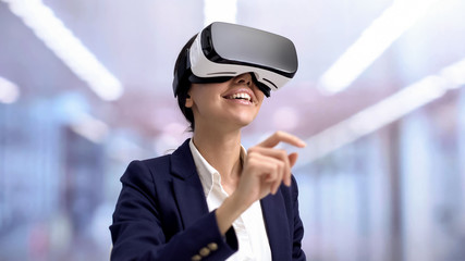 Smiling manager in virtual reality headset scrolling images, office technology