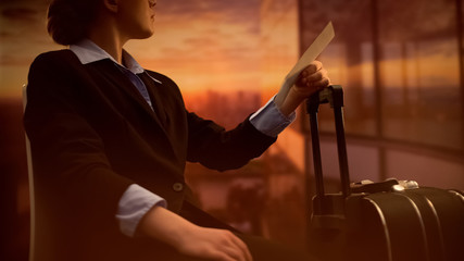 Female with luggage holding ticket, waiting for flight at airport, dreaming
