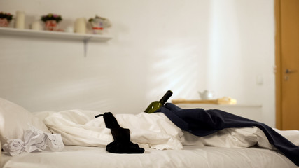 Lingerie and bottles lying on bed after students home party, cleaning service