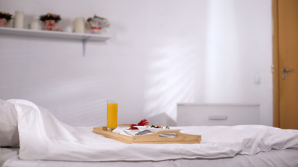 Tray with food standing on white bed, food order in hotel room, quality service